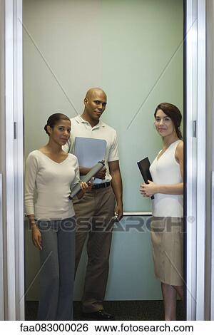 Young office workers standing in elevator View Large Photo Image Stock Photograph - Young office workers standing in elevator. Fotosearch