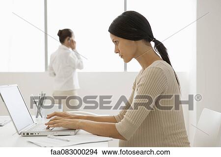 Young pregnant woman typing on laptop computer in office, backlit View Large Photo Image Picture - Young pregnant woman typing on laptop computer in office, backlit. Fotosearch