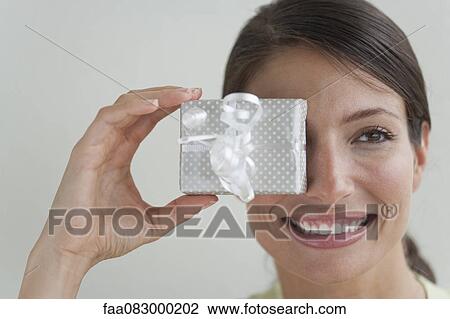 Young woman covering eye with gift View Large Photo Image Stock Image - Young woman covering eye with gift. Fotosearch