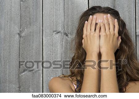 Young woman covering face with hands, portrait View Large Photo Image Picture - Young woman covering face with hands, portrait. Fotosearch