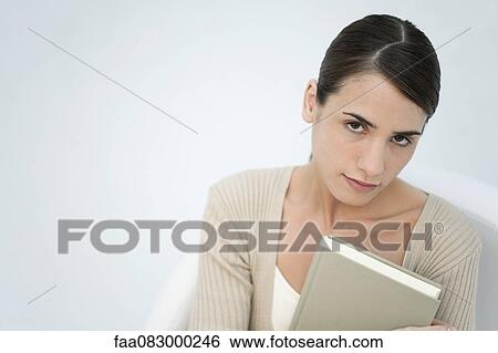 Stock Photograph - Young woman holding book, portrait. Fotosearch