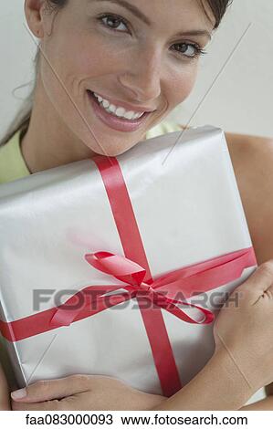 Stock Image - Young woman holding gift. Fotosearch