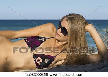 Young woman in bikini reclining at beach View Large Photo Image Stock Photograph - Young woman in bikini reclining at beach. Fotosearch