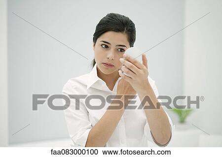 Young woman looking at self in hand mirror View Large Photo Image Stock Image - Young woman looking at self in hand mirror. Fotosearch