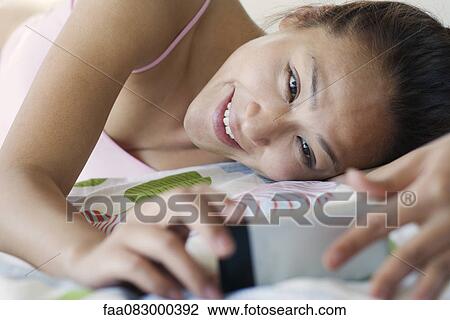 Young woman lying down in underwear, looking at cell phone View Large Photo Image Stock Image - Young woman lying down in underwear, looking at cell phone. Fotosearch