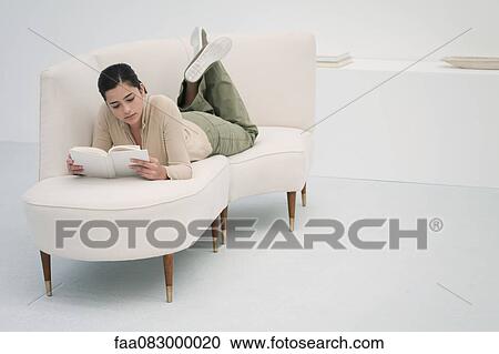 Young woman lying on chaise longue, reading book View Large Photo Image Stock Image - Young woman lying on chaise longue, reading book. Fotosearch