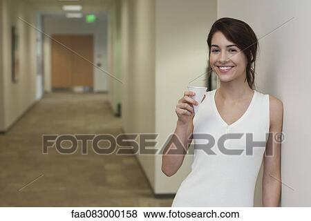 Young woman standing in corridor holding disposable cup View Large Photo Image Stock Photo - Young woman standing in corridor holding disposable cup. Fotosearch