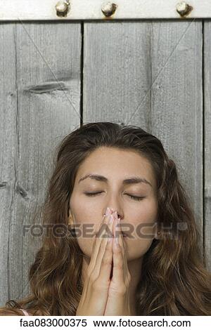 Young woman with hands clasped in front of mouth, eyes closed View Large Photo Image Stock Photography - Young woman with hands clasped in front of mouth, eyes closed. Fotosearch