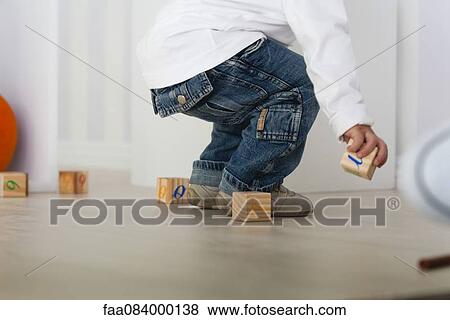 Stock Photo - Baby picking up block from floor, low section. Fotosearch
