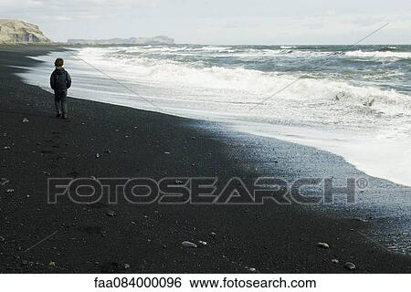 Boy walking on the beach watching the horizon, iceland View Large Photo Image Stock Photograph - Boy walking on the beach watching the horizon, iceland. Fotosearch
