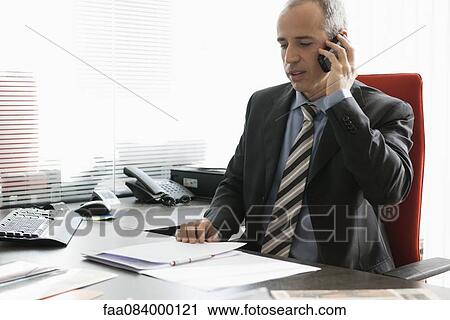 Business executive talking on cell phone in office View Large Photo Image Stock Image - Business executive talking on cell phone in office. Fotosearch