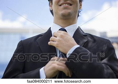 Businessman adjusting tie View Large Photo Image Stock Image - Businessman adjusting tie. Fotosearch