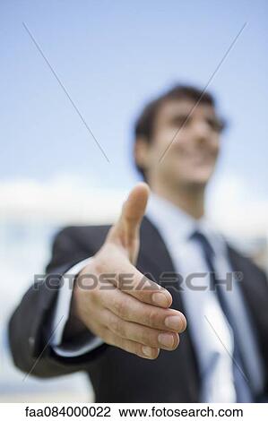 Stock Image - Businessman extending hand for handshake, low angle view. Fotosearch