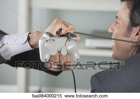Businessman with video game controller cable tied around neck by colleague, cropped View Large Photo Image Stock Photography - Businessman with video game controller cable tied around neck by colleague, cropped. Fotosearch