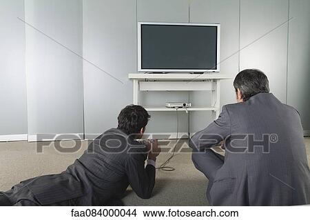 Picture - Businessmen playing video game, rear view. Fotosearch