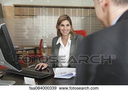 Stock Photo - Businesswoman assisting client in office. Fotosearch