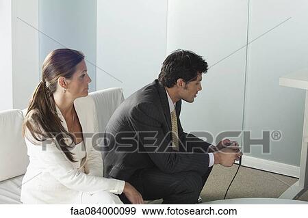 Businesswoman watching businessman playing video game View Large Photo Image Stock Photo - Businesswoman watching businessman playing video game. Fotosearch