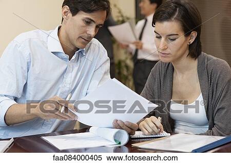 Stock Photography - Colleagues discussing document in office. Fotosearch