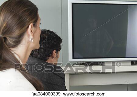 Stock Photo - Colleagues watching television, side view. Fotosearch
