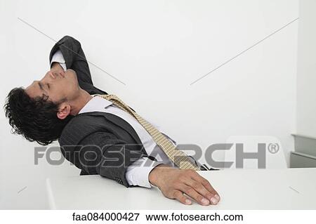 Exhausted mid-adult businessman leaning back on chair with eyes closed View Large Photo Image Stock Photo - Exhausted mid-adult businessman leaning back on chair with eyes closed. Fotosearch