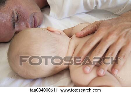 Stock Image - Father napping with baby. Fotosearch