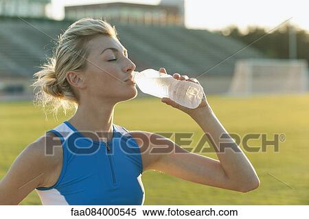 Stock Photography - Female athlete drinking bottled water. Fotosearch