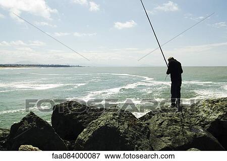 Fisherman and his fishing rod, port of Biarritz on the horizon View Large Photo Image Stock Photo - Fisherman and his fishing rod, port of Biarritz on the horizon. Fotosearch