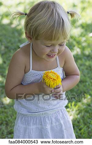 Stock Image - Little girl holding flower, portrait. Fotosearch
