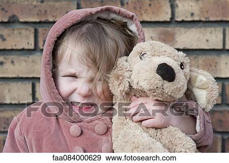 Stock Photo - Little girl hugging stuffed dog, portrait. Fotosearch