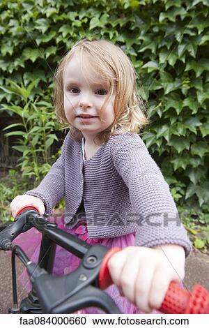 Stock Image - Little girl with bicycle, portrait. Fotosearch