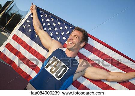 Stock Photo - Male athlete holding up American flag. Fotosearch