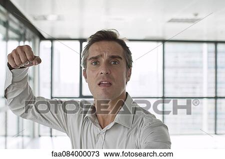 Stock Image - Man looking at camera with fist raised in air. Fotosearch