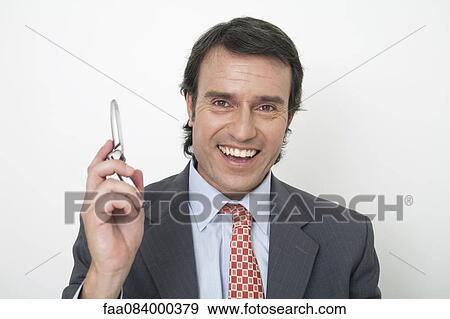 Stock Photo - Mature businessman holding cell phone, smiling. Fotosearch