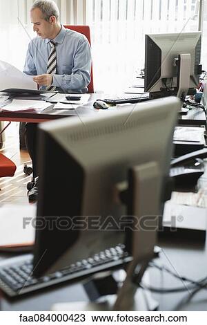Stock Image - Mature businessman working in office. Fotosearch
