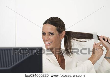 Mature businesswoman brushing hair at desk View Large Photo Image Stock Image - Mature businesswoman brushing hair at desk. Fotosearch