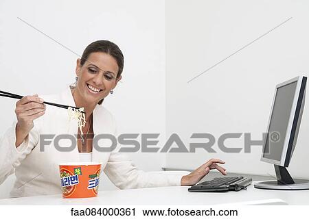Mature businesswoman eating instant noodles at desk View Large Photo Image Stock Image - Mature businesswoman eating instant noodles at desk. Fotosearch