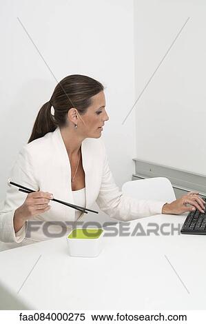 Mature businesswoman eating lunch with chopsticks at desk View Large Photo Image Stock Photography - Mature businesswoman eating lunch with chopsticks at desk. Fotosearch