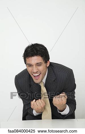 Mid-adult businessman clenching fists in celebration View Large Photo Image Stock Photography - Mid-adult businessman clenching fists in celebration. Fotosearch