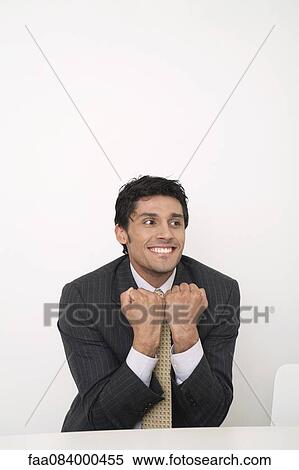 Mid-adult businessman clenching fists in front of chest, smiling View Large Photo Image Stock Photography - Mid-adult businessman clenching fists in front of chest, smiling. Fotosearch