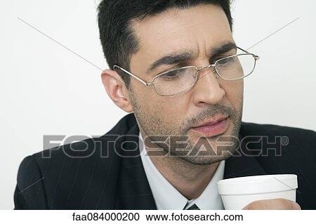 Stock Image - Mid-adult businessman holding disposable cup. Fotosearch