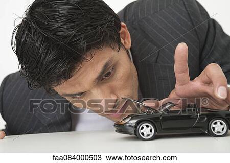 Mid-adult businessman looking at toy car View Large Photo Image Stock Image - Mid-adult businessman looking at toy car. Fotosearch