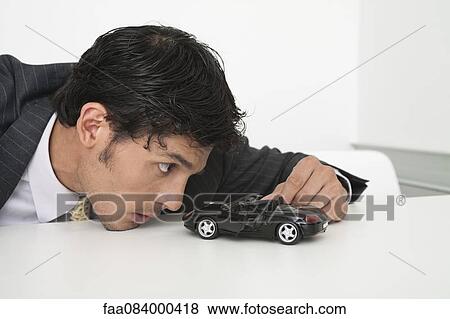 Mid-adult businessman looking at toy car View Large Photo Image Stock Photo - Mid-adult businessman looking at toy car. Fotosearch