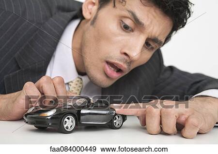 Mid-adult businessman looking at toy car View Large Photo Image Stock Photo - Mid-adult businessman looking at toy car. Fotosearch
