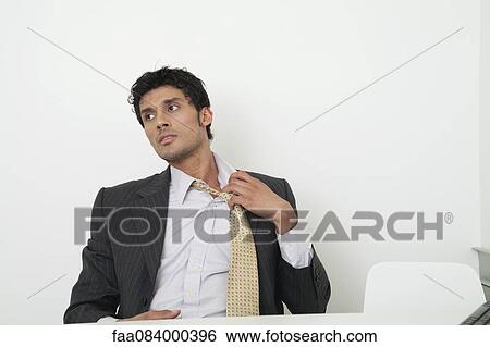 Mid-adult businessman pulling off tie View Large Photo Image Stock Photograph - Mid-adult businessman pulling off tie. Fotosearch