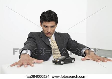 Mid-adult businessman staring at toy car View Large Photo Image Picture - Mid-adult businessman staring at toy car. Fotosearch