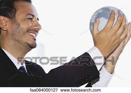 Mid-adult executive holding globe, side view View Large Photo Image Stock Photo - Mid-adult executive holding globe, side view. Fotosearch