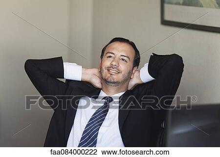 Mid-adult executive relaxing with hands behind head View Large Photo Image Stock Image - Mid-adult executive relaxing with hands behind head. Fotosearch