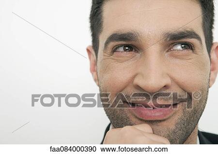 Stock Image - Mid-adult man daydreaming, smiling. Fotosearch