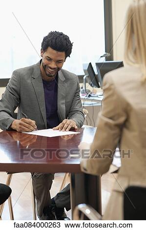 Stock Image - Professional man completing application at job interview. Fotosearch