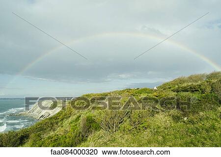 Stock Image - Rainbow on the cliffs of Ciboure, France. Fotosearch